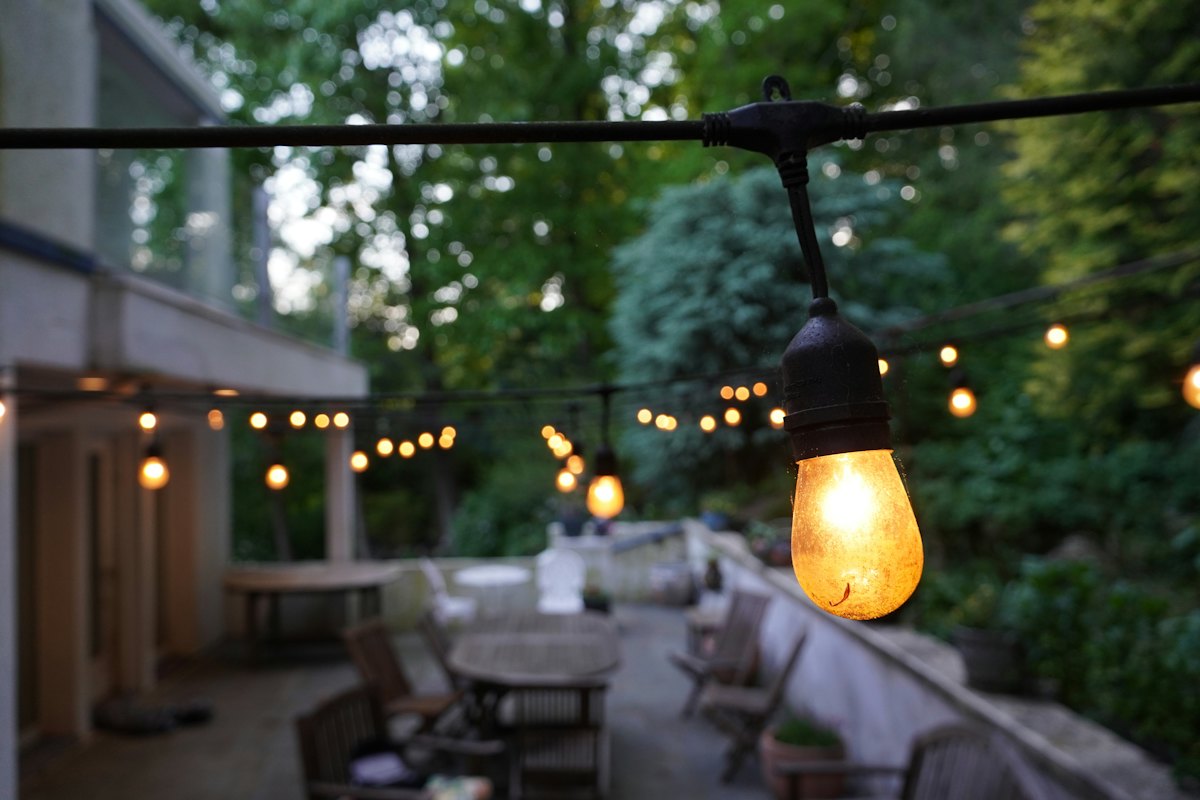 Backyard patio dining area under string lights at dusk