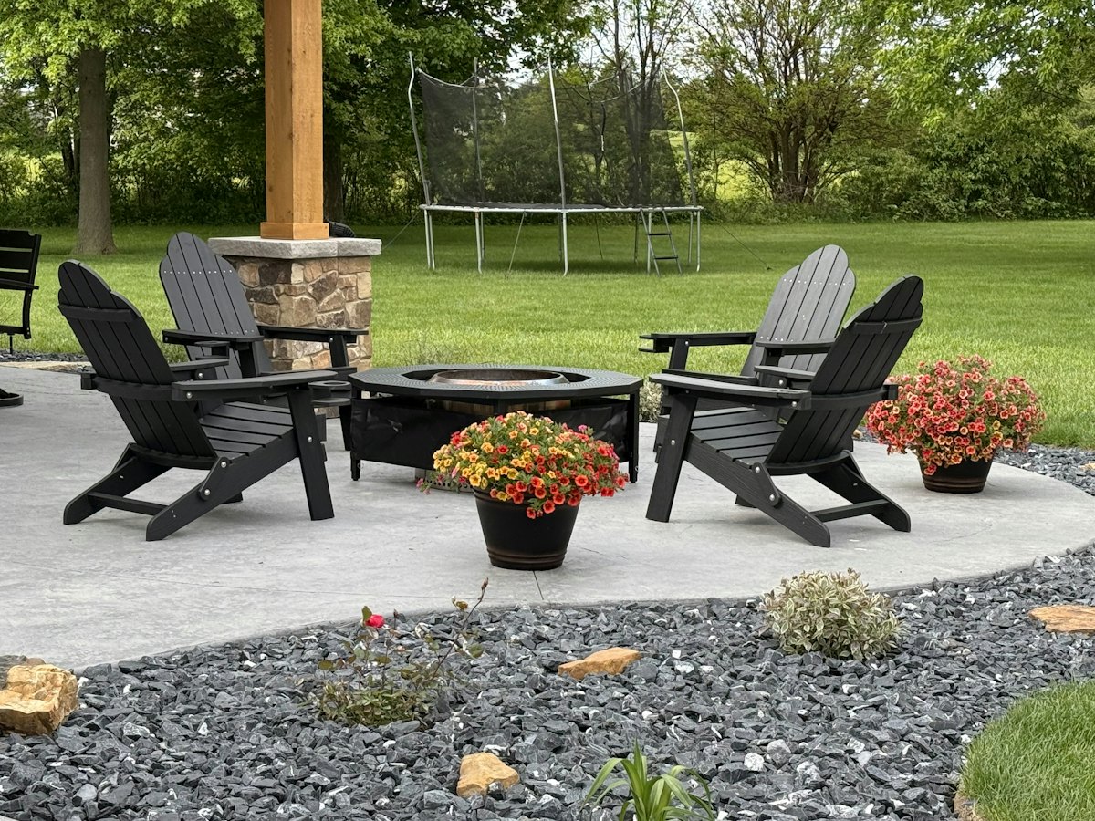 Curved concrete patio with a fire pit and adirondack chairs