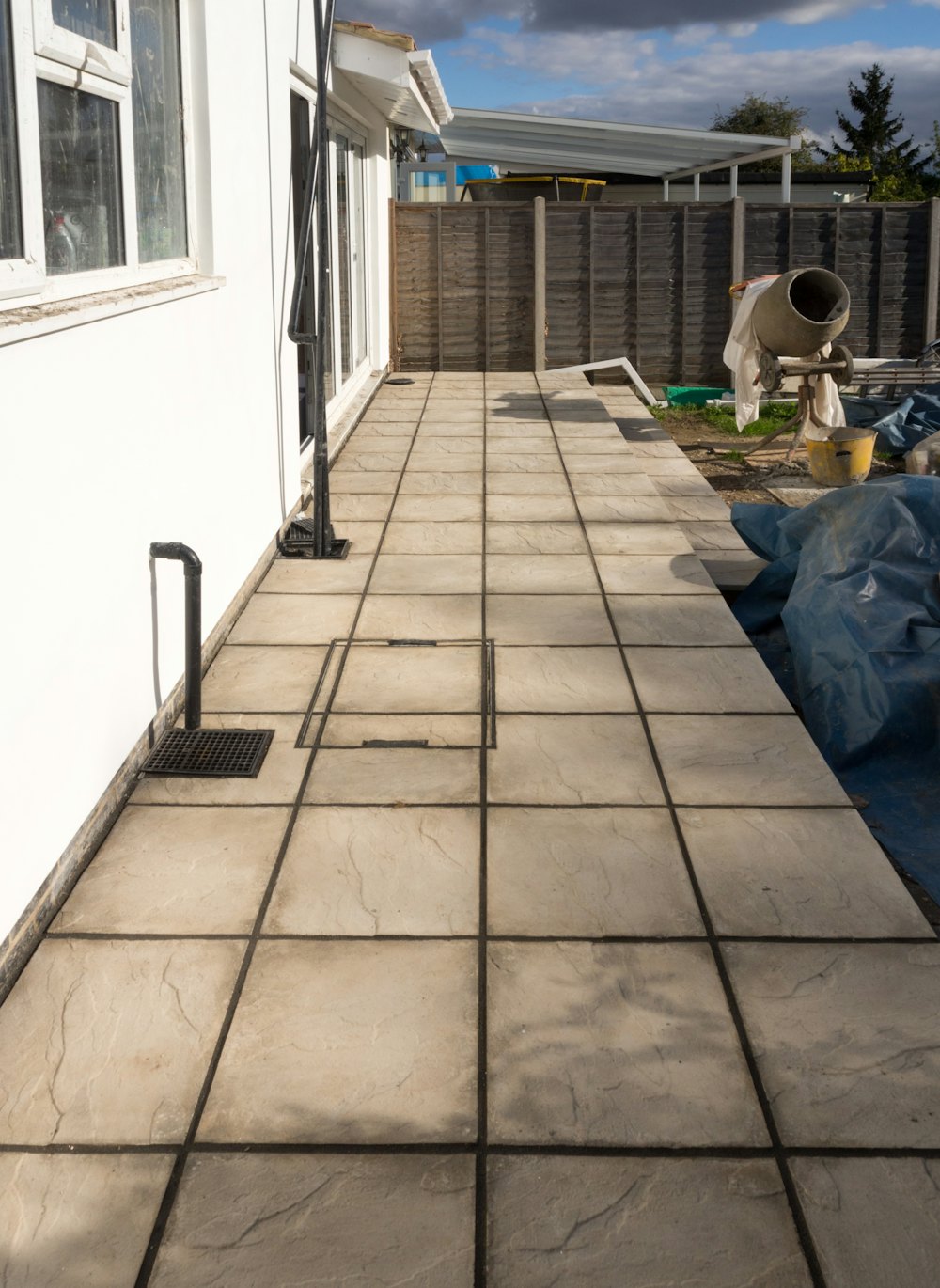 Worker finishing a concrete patio beside a house